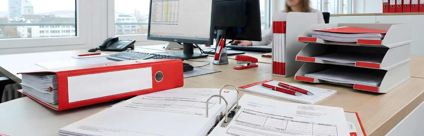 Schreibtisch mit Laptop, Steuerdokumenten, Taschenrechner und Notizzetteln – symbolisches Bild für Lohnbuchhaltung in der Schweiz und administrative Aufgaben von KMU, unterstützt durch die Rothstein AG Treuhand aus Oftringen im Kanton Aargau.